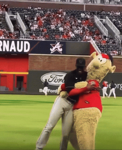 Mascot Hugging Baseball Player With Ford Sign GIF