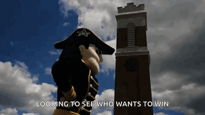 Mascot In Front Of Clock Tower Saying Looking To See Who Wants To Win GIF