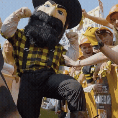 Mascot In Plaid Shirt And Suspenders In Crowd GIF