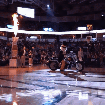 Mascot Riding Motorcycle On Basketball Court With Scoreboard 130 GIF