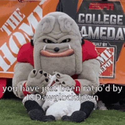 Mascot Sitting On Grass In Front Of Home Depot Sign GIF