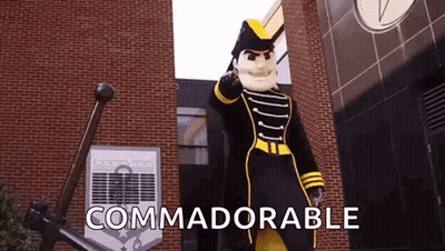 Mascot Standing In Front Of Brick Building Saying Commadorable GIF