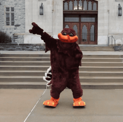 Mascot Standing In Front Of Building Pointing GIF