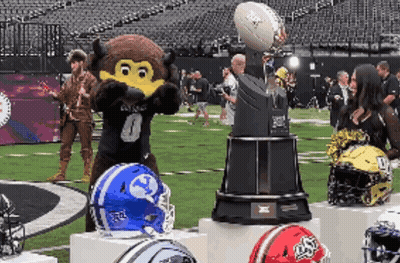 Mascot Standing Next To Trophy With Football GIF