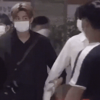 Masked Man Holding Another's Hand In Crowd GIF