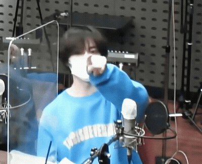Masked Man In Blue Sweater At Microphone GIF