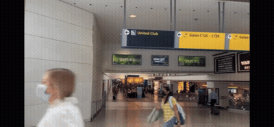 Masked Woman At Airport Holding United Club Sign GIF