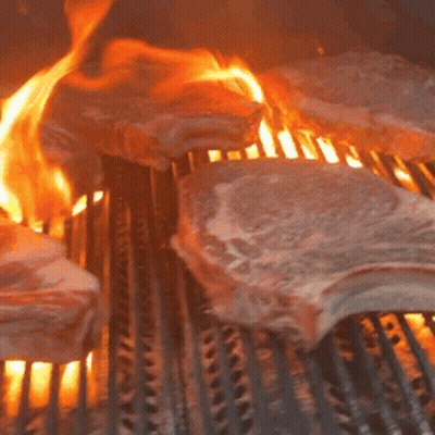 Meat Is Being Cooked On A Grill With Flames Coming Out Of It GIF