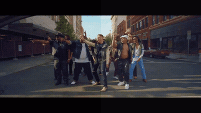 Men Dancing On Street In Front Of Brick Building GIF