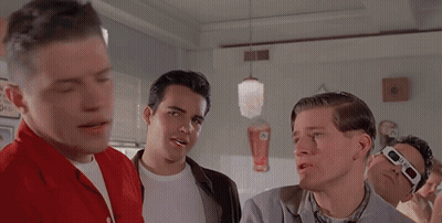 Men Gathered Around Diner Table With Behind Sign GIF