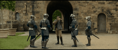 Men In Armor Standing Before Stone Building GIF