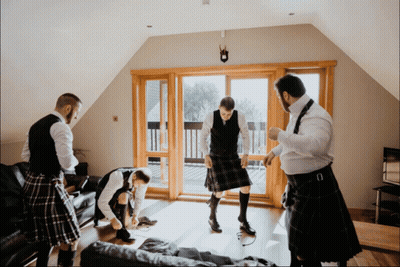 Men In Kilts Standing In Living Room GIF