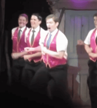 Men In Pink Vests And Ties On Stage GIF