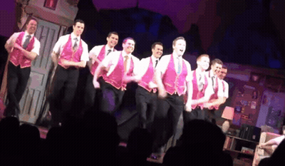 Men In Pink Vests Dancing On Stage GIF