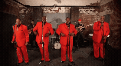 Men In Red Suits Singing Into Microphones GIF