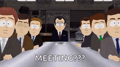 Men In Suits Sitting Around Table With Man At Head GIF