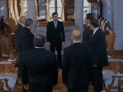 Men In Suits Standing Around Table GIF