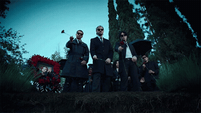 Men In Suits Standing Before Wreath GIF