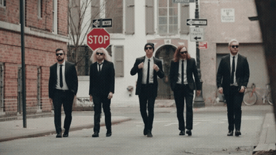 Men In Suits Walking Past Stop Sign GIF