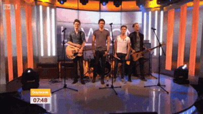 Men Playing Guitars On Stage At 7:48 GIF