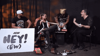 Men Sitting Around Sign Saying Hey GIF