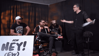 Men Sitting In Front Of Hey Sign GIF