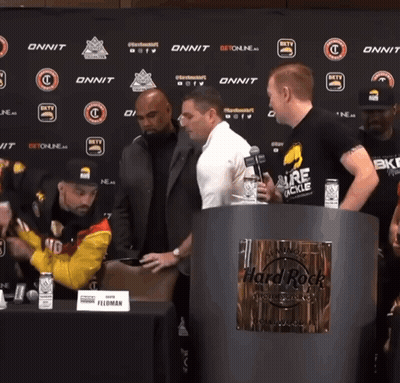 Men Standing Around Hard Rock Sign GIF