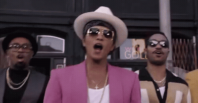 Men Standing In Front Of Building, One In Pink Jacket And Hat GIF