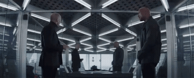 Men Standing In Room With Table And Mirror GIF