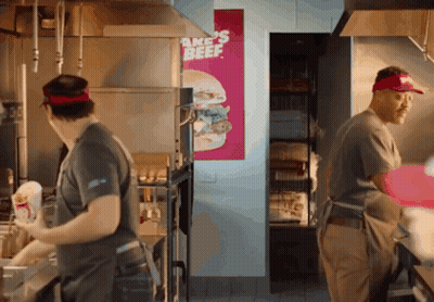 Men Working in Kitchen With Bake's Beef Sign
