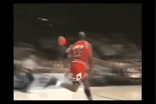 Michael Jordan Is Jumping In The Air While Holding A Basketball In His Hand . GIF