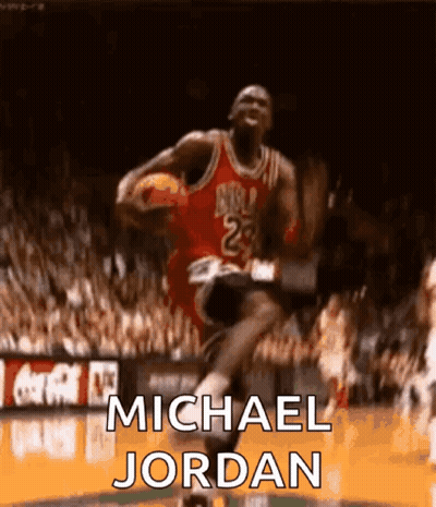 Michael Jordan Is Jumping In The Air With A Basketball In His Hand . GIF