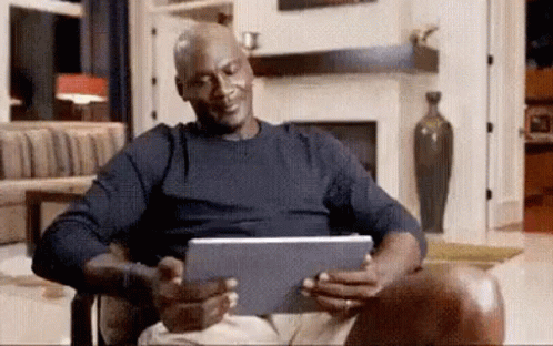 Michael Jordan Is Sitting In A Chair Looking At A Tablet Computer . GIF