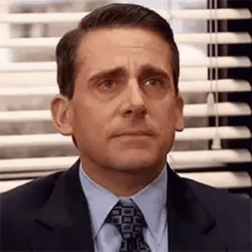 Michael Scott Is Wearing A Suit And Tie And Looking At The Camera . GIF