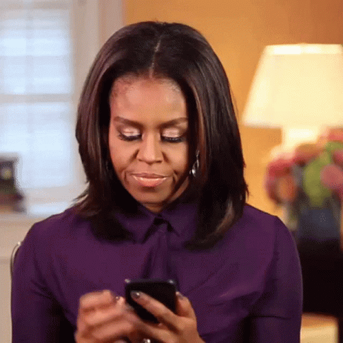 Michelle Obama In Purple Shirt Looking At Phone GIF