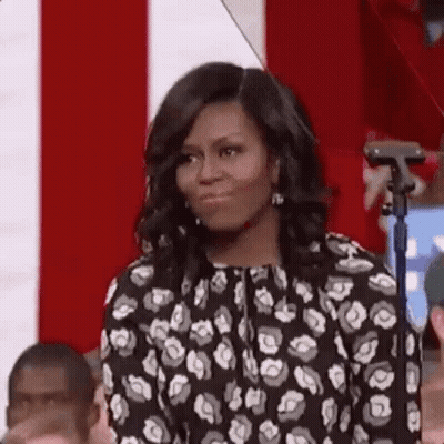 Michelle Obama Is Standing In Front Of A Microphone In Front Of A Crowd . GIF