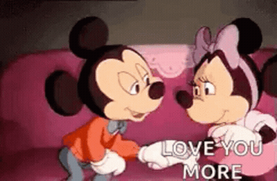 Mickey Mouse And Minnie Mouse Are Sitting On A Pink Couch Holding Hands And Looking At Each Other . GIF