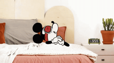 Mickey Mouse Is Laying On A Bed Next To A Clock That Says 5:59 GIF