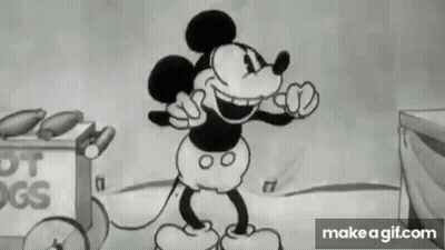 Mickey Mouse Standing In Front Of Hot Dog Cart GIF