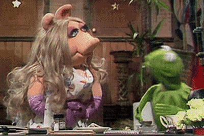Miss Piggy And Kermit The Frog Are Sitting At A Table In A Kitchen . GIF