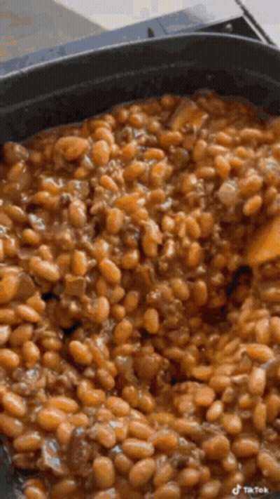 Monkey Sitting On Counter Eating Green Beans While Person Cuts Them GIF