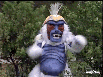Monkey With Blue Face And White Fur Standing In Front Of Trees GIF