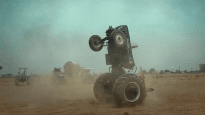 Monster Truck Doing Trick On Dirt Road GIF