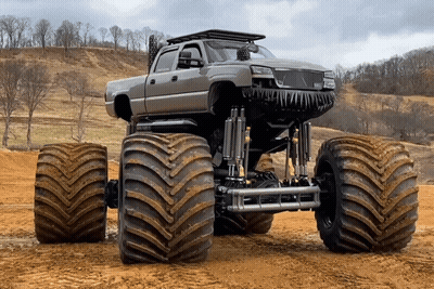 Monster Truck With Huge Tires Parked In Dirt Field GIF