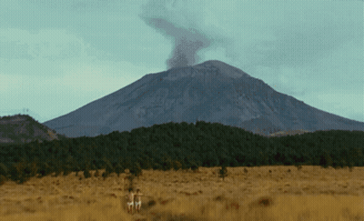 Mountain With Smoke Surrounded By Trees And Grass GIF
