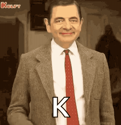 Mr Bean In Suit And Tie With Letter K On Chest GIF