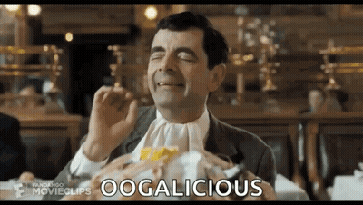 Mr Bean Is Eating A Hamburger In A Restaurant While Wearing A White Tie . GIF