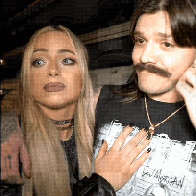 Mustached Man Next To Woman Wearing Dan Morgan GIF