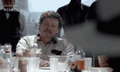 Mustached Man Sitting At Table With Glasses GIF