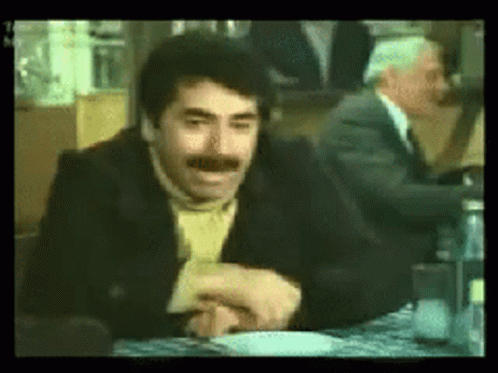 Mustached Man Sitting With Another At Table GIF
